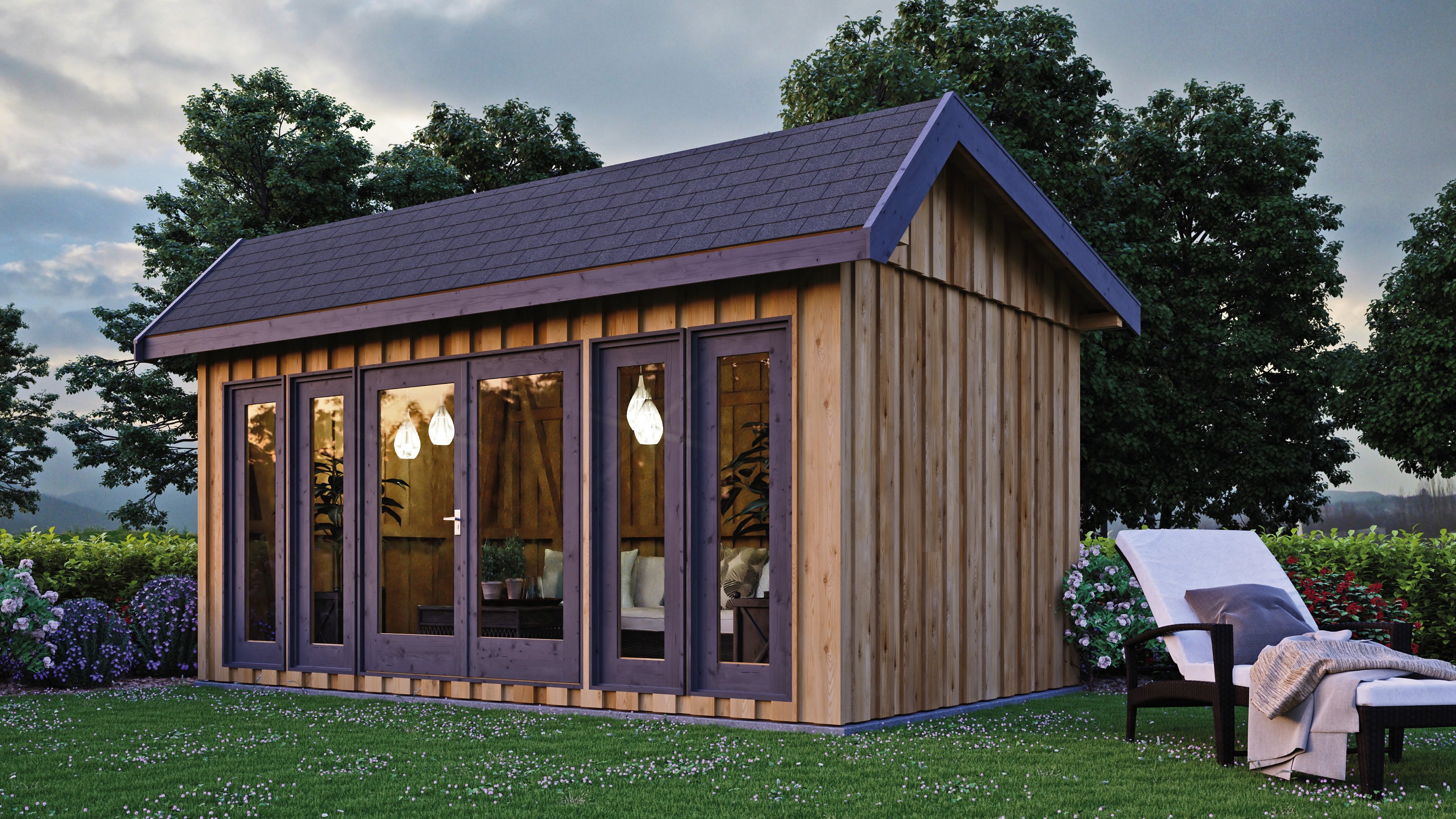 Modernes Gartenhaus aus Holz mit Satteldach, bodentiefen Fenstern und gemütlich beleuchtetem Innenraum, davor Liegestuhl im Garten