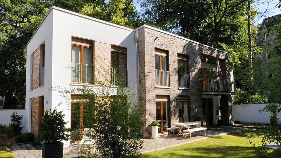 Modernes Stadthaus mit heller Putz- und dunkler Klinkerfassade sowie kleinem Garten