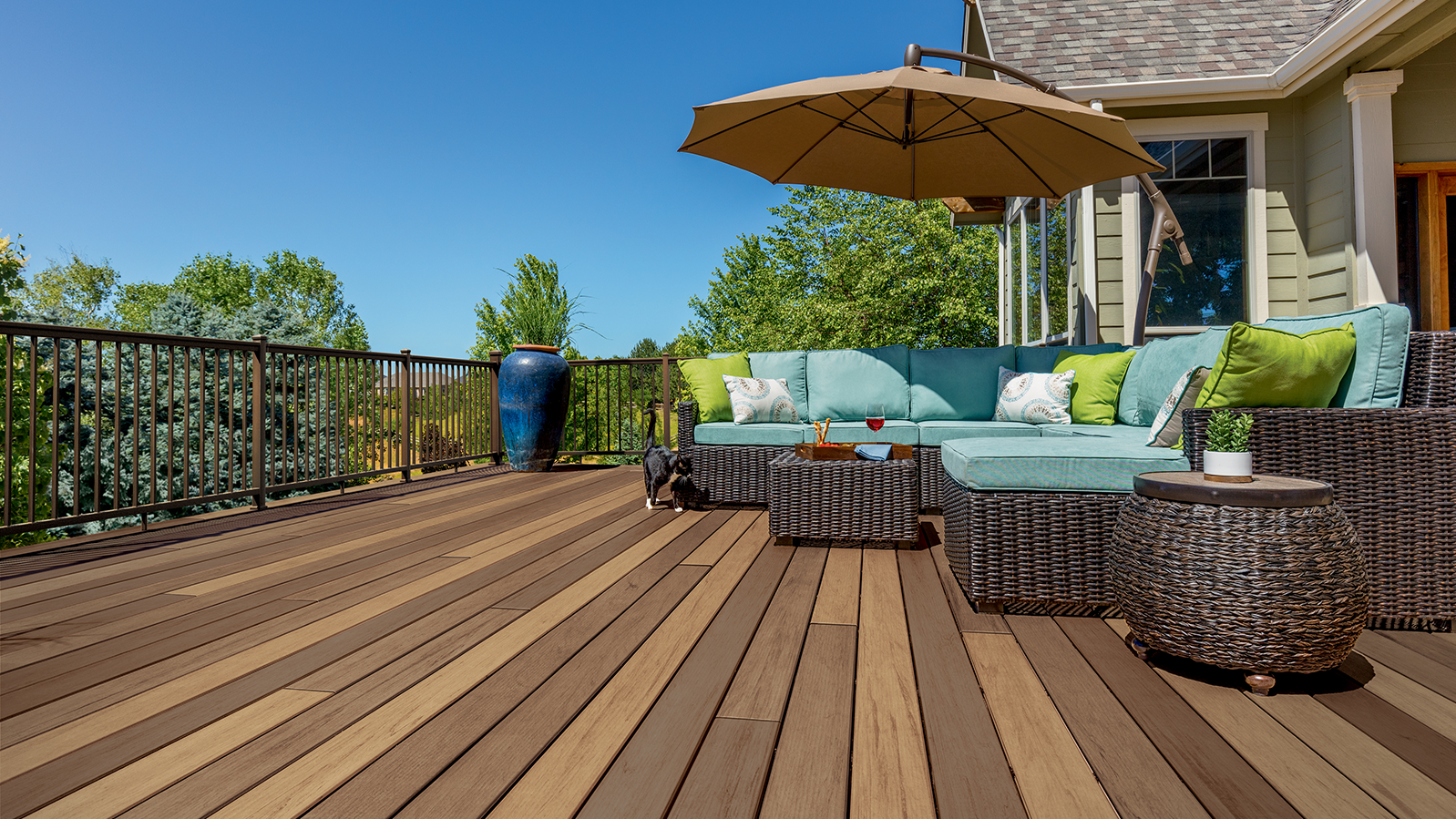 Sonnige Holzterrasse mit gemütlicher Loungelandschaft, Sonnenschirm und Ausblick auf den Garten