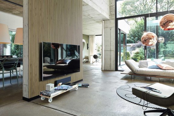 Offener Wohnbereich mit Holz-Akustikpaneelen, Designmöbeln und bodentiefen Fenstern