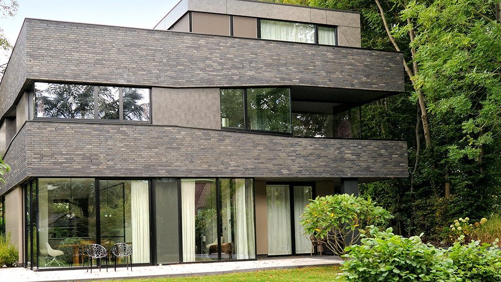 Modernes Wohnhaus mit dunkler Klinkerfassade und großen Fensterflächen