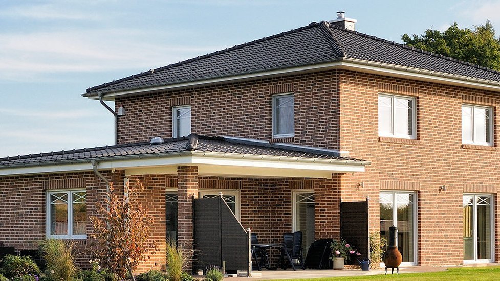 Zweistöckiges Klinkerhaus mit dunklem Dach und überdachter Terrasse