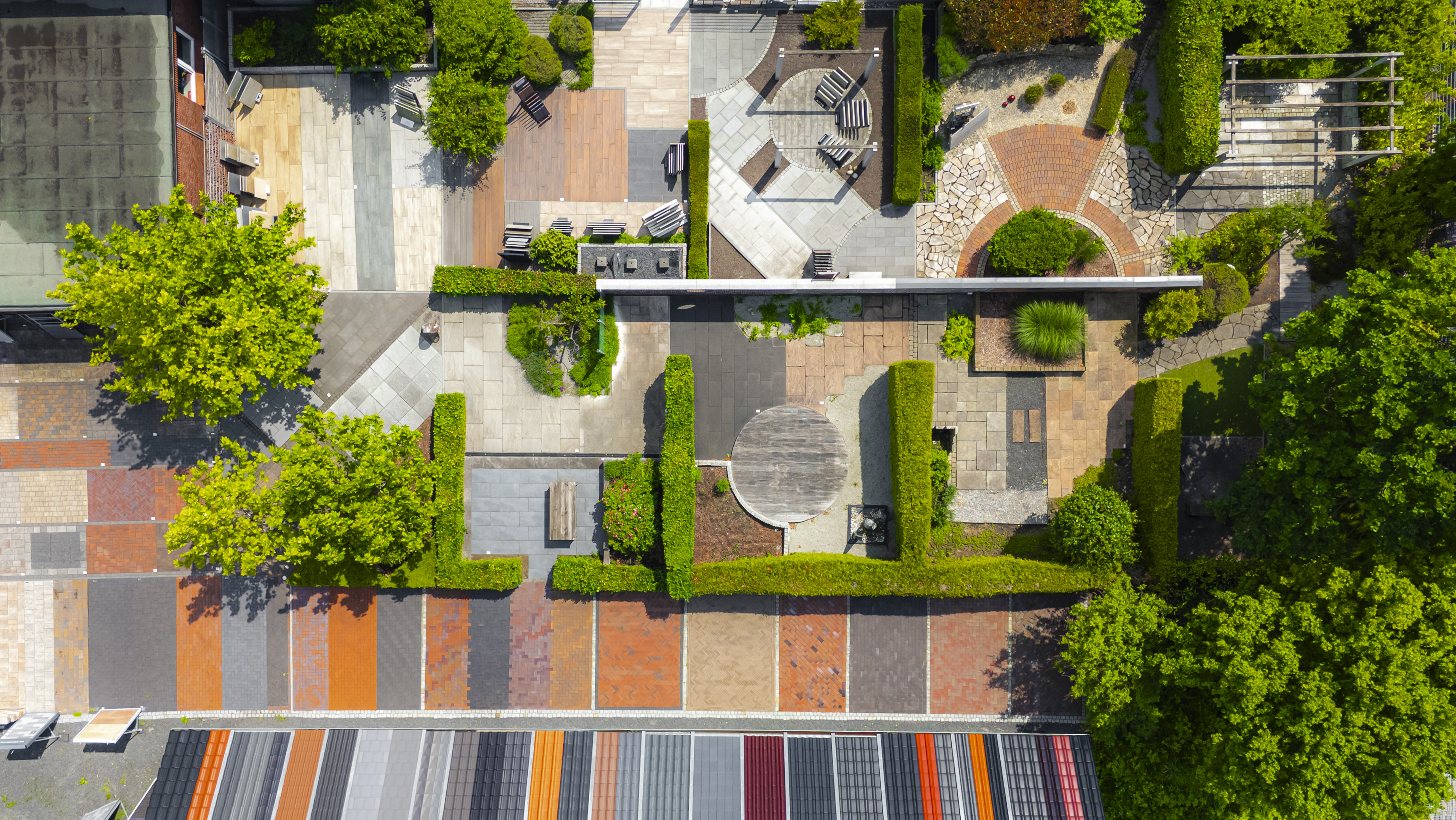 Perspektivaufnahme des Mustergartens in Kirchwerder mit gemauerter Ziegelwand, Dachmustern, Gartenwegen und modernen Outdoorflächen.