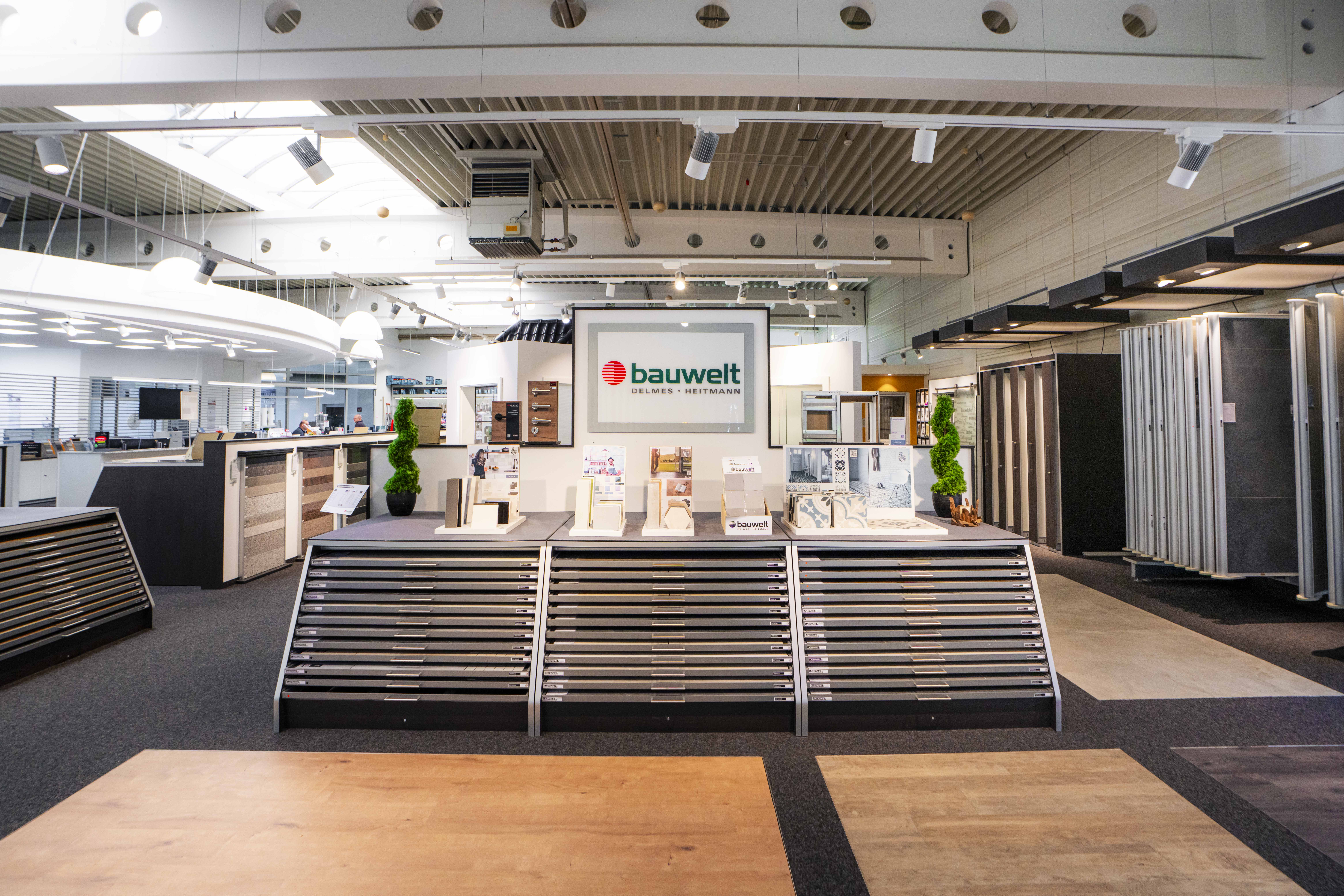 Moderne Innenansicht der Bauwelt-Ausstellung in Buchholz mit Materialmustern, Bodenbelägen und Informationsständen.
