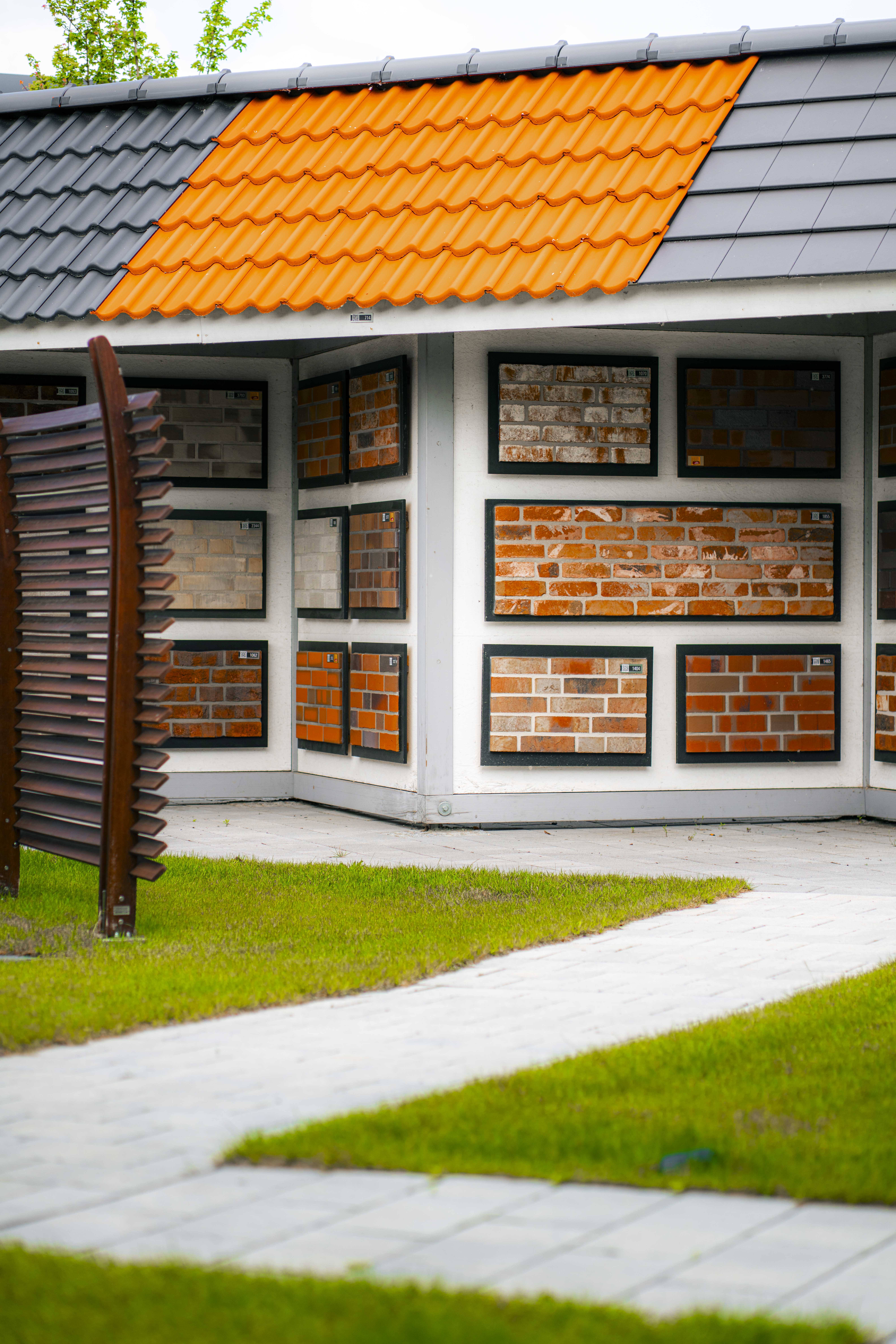 Musterpavillon mit verschiedenen Dachziegeln und Klinkerfassaden auf einer begrünten Ausstellungsfläche.