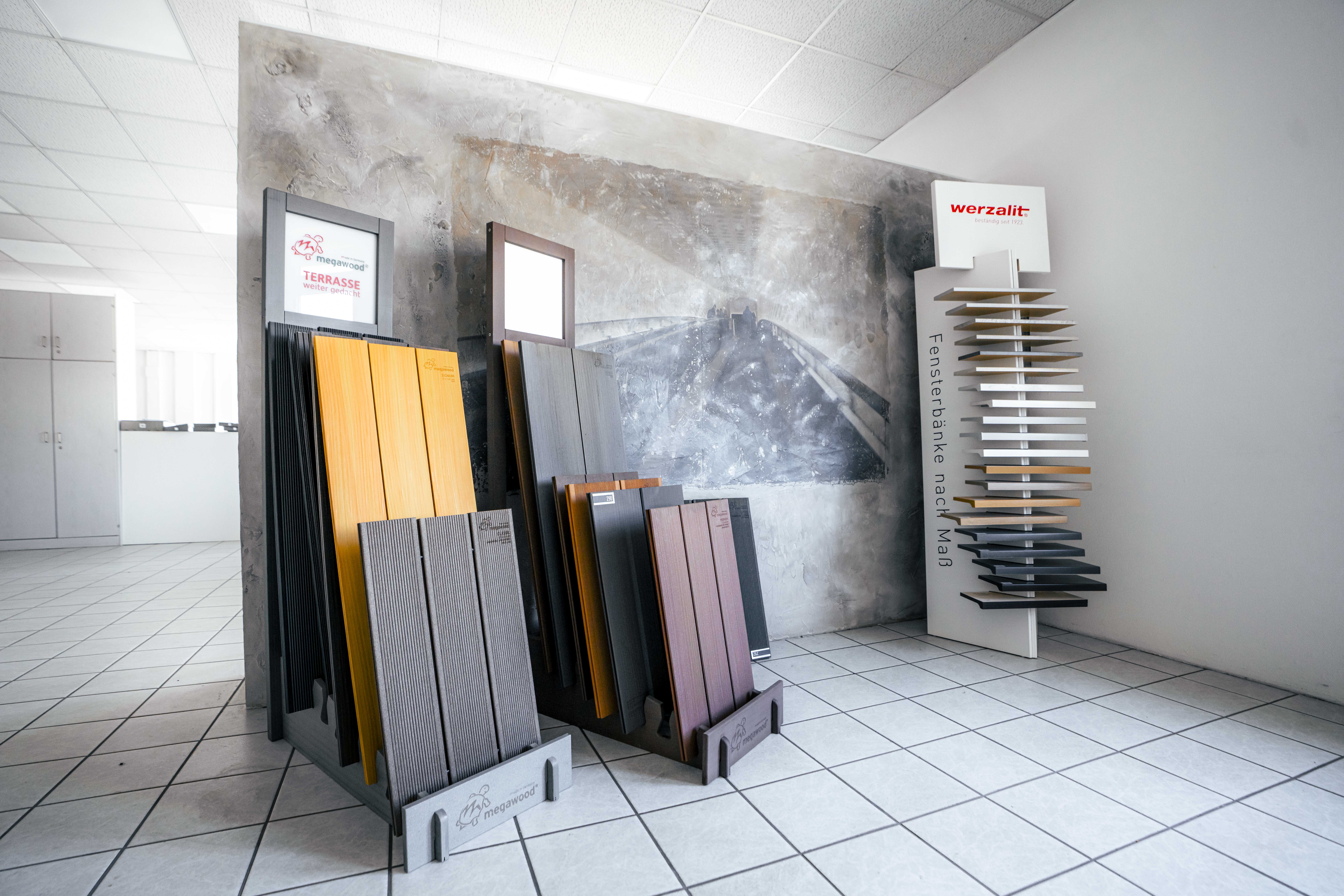Innenbereich mit Ausstellungsflächen für Terrassendielen und Fensterbänke bei Bauwelt Hummelsbüttel, präsentiert auf modernen Aufstellern in einem gefliesten Raum.